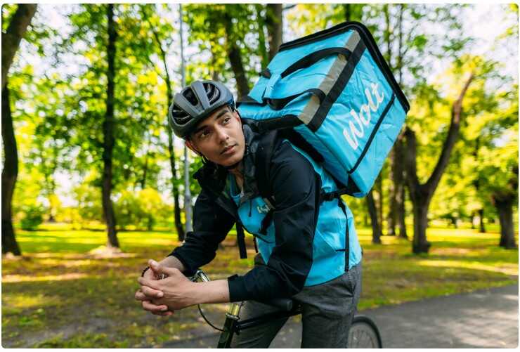 Lieferant fährt auf dem Fahrrad durch den Park
